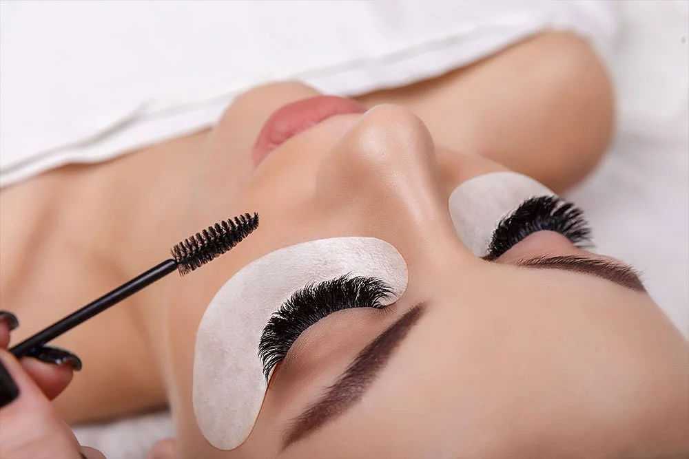 Woman receiving eyelash extension service at a salon.